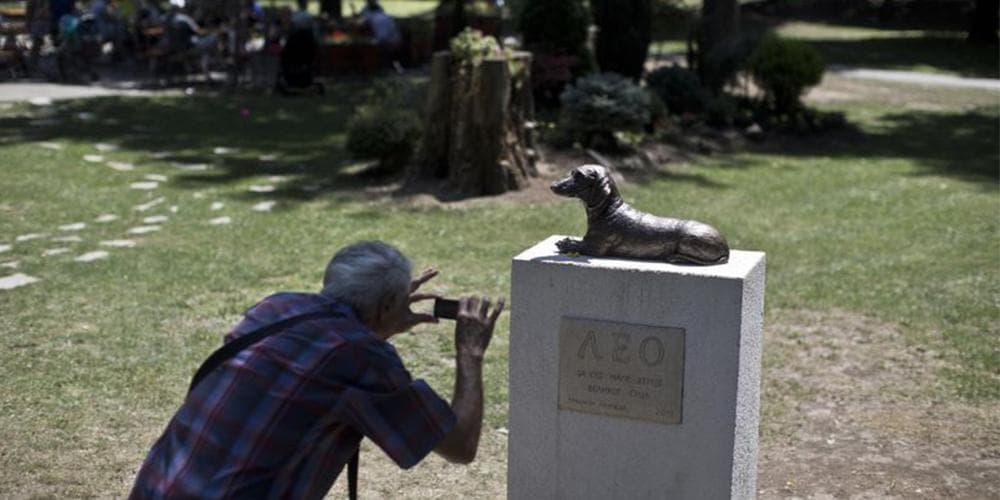 A man takes a photo of the monument to Leo, a dachshund that defended a child from an attack by another dog, at a public park in Serbia. (Marko Drobnjakovic/AP)